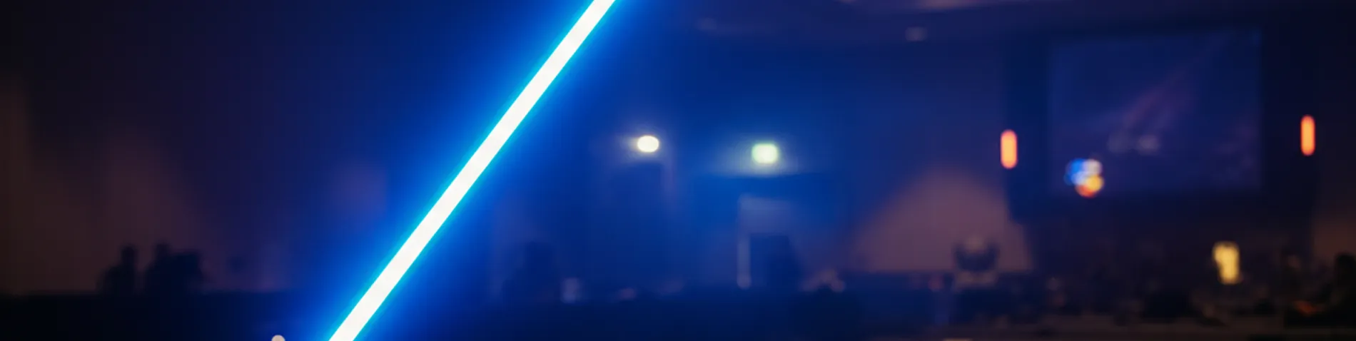 Espada láser azul iluminando una sala oscura en una celebración friki