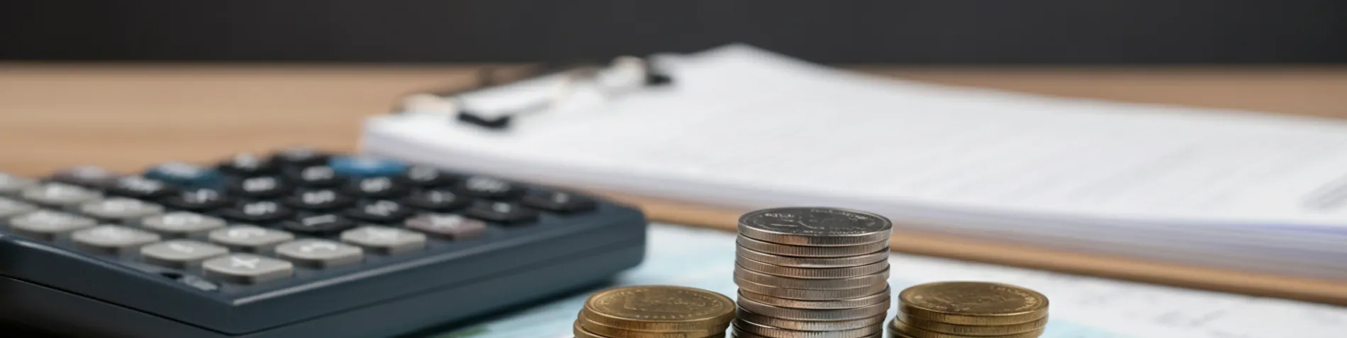Calculadora, formulario de la declaración de la renta y monedas sobre una mesa de oficina
