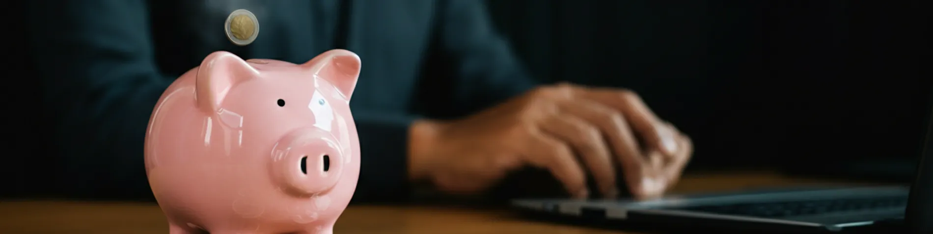 Hucha generando monedas de forma automática mientras una persona descansa al fondo en un escritorio