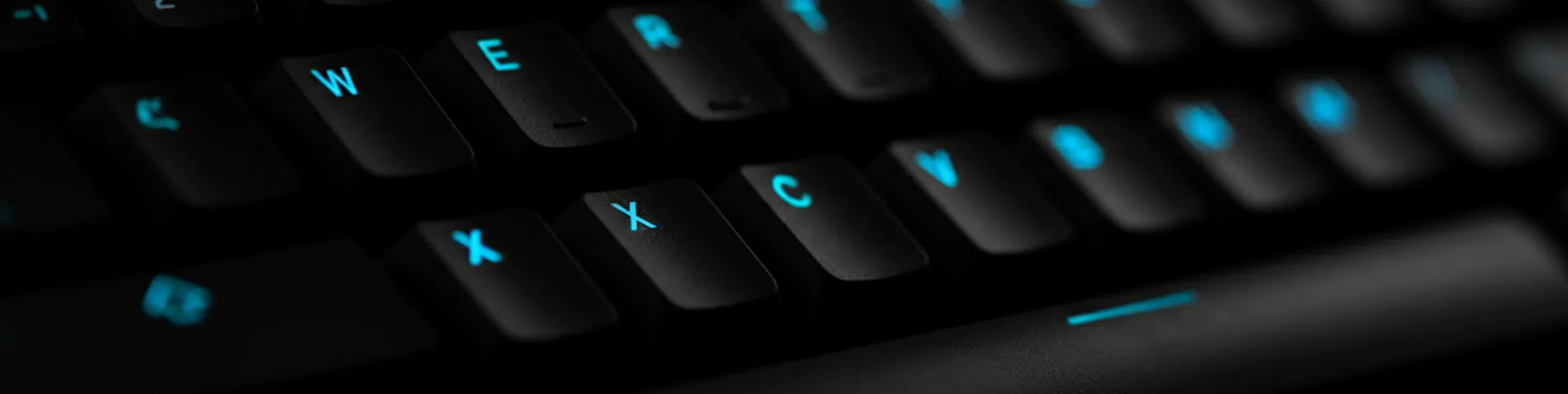 Teclado en primer plano con las teclas de símbolos matemáticos y de comparación iluminadas sobre un fondo oscuro