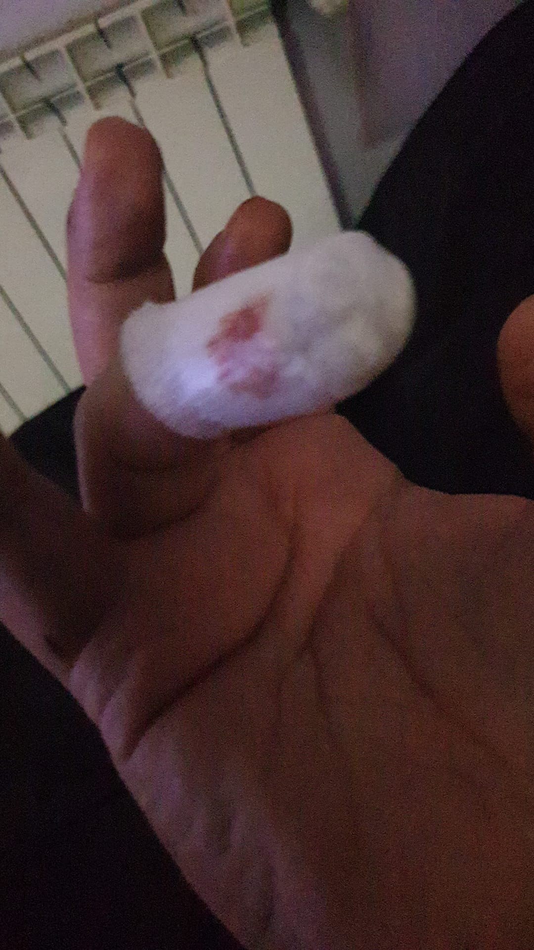Gasa de la cura con una mancha de sangre, sujeta entre los dedos